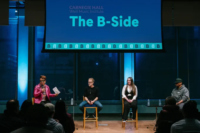 A photo of four people sitting on a stage, with Laurie Cumbo on the far left holding a microphone. They're seated under a sign that reads "Carnegie Hall Weill Music Institute The B-Side."