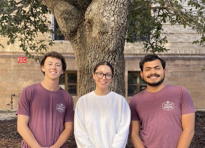 Ellis, Diana, and Umesh pose smiling in front of a tree.
