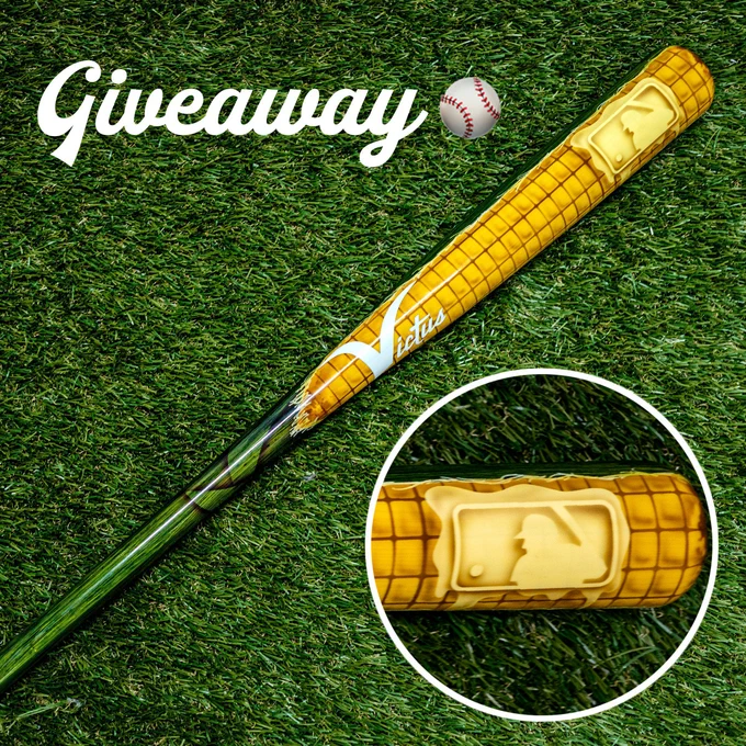 A baseball bat sitting on grass. The bat is designed as a corncob. The butter slice has the MLB batterman logo in it. "Giveaway" with a. baseball emoji is written in the upper left corner.