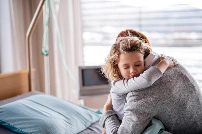 A little girl hugging a woman in a hospital