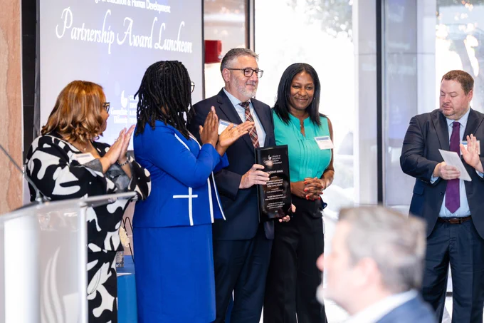 Brian Keefer from Fulton County Schools holds up the Partnership Award plaque and smiles while Dionne Cowan, DaShaunda Patterson, Tracy Ware and Nick Sauers look on