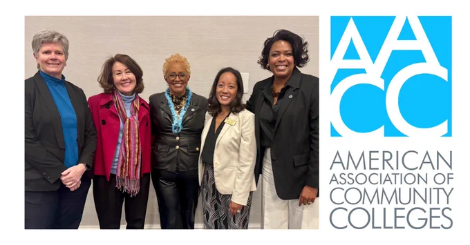 Five professionally dressed women standing together and smiling next to the American Association of Community Colleges logo.