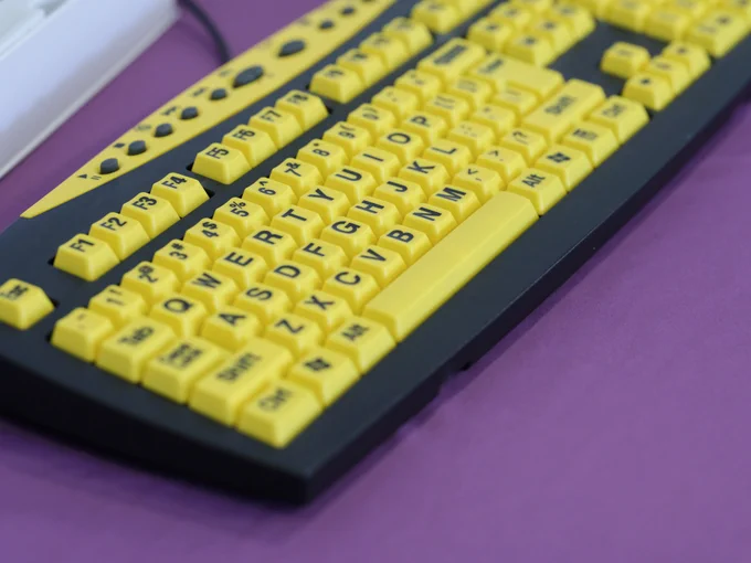 High-contrast yellow and black keyboard on a purple surface, designed for visibility assistance.