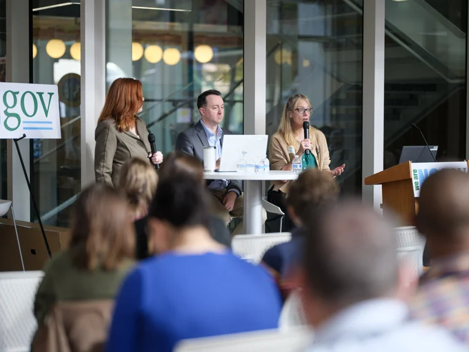 Three professionals seated at a panel discussion in front of an audience