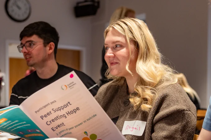 An event participant reading a document and smiling.