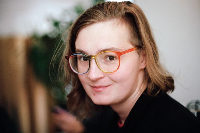 a beautiful blonde woman in sharp focus looking at the camera in love with vibrant rainbow glasses framing her eyes