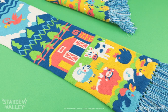 Closeup photo of one end of a colorful Stardew Valley scarf, showing its blue and white fringe. Cute, colorful animals stand in front of a barn in the foreground; the picture stretches into the sky as the scarf gets longer, cutting off in the photo as it seems to transition into space