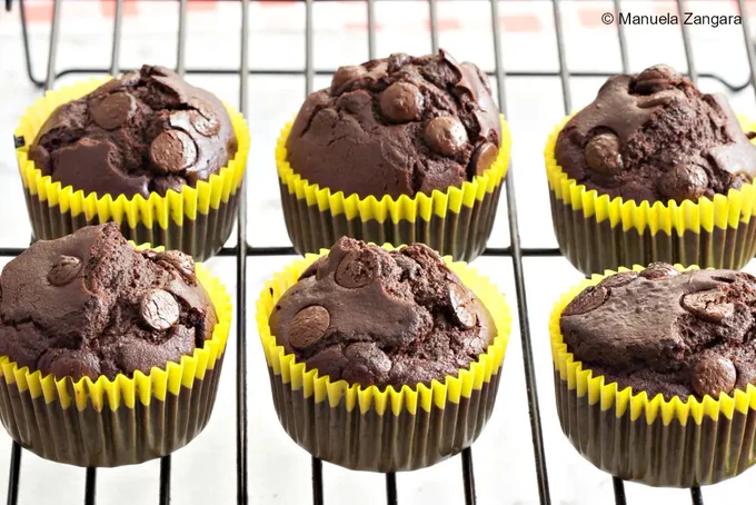 Several baked dairy-free chocolate muffins cooling on a wire rack.