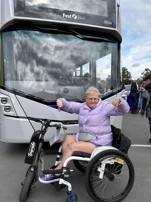Me sat in my wheelchair in front of a First bus giving a double thumbs down
