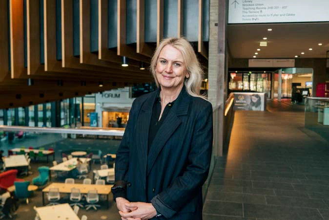 Photo of Carolyn smiling at the camera. She is stood in a large venue.