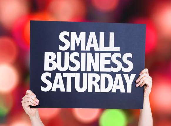 Image of a sign being held up, text reads, “SMALL BUSINESS SATURDAY”, with blue background, white text. 