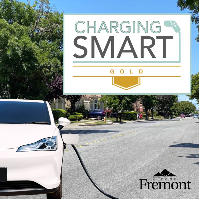 White electric car plugged into a charger on a Fremont street with the Charging Smart Gold logo and the City of Fremont logo
