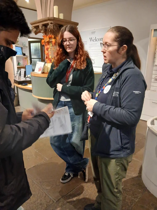 A Museum staff member and young person explain the maps to a visitor.