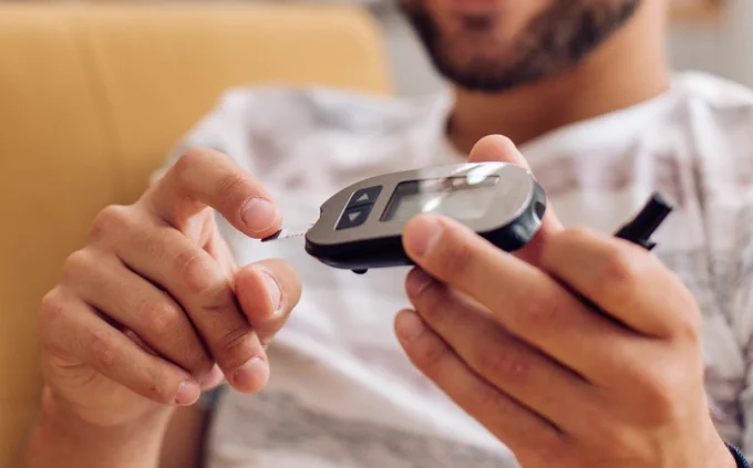 Young man measuring insulin level at home.