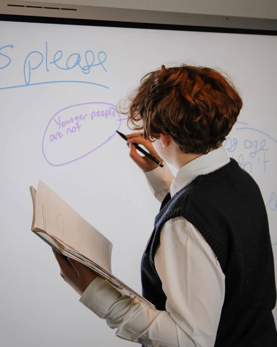 Clear Touch student K-12 using pen to draw and write on the smart board / interactive flat panel to demonstrate knowledge to classmates