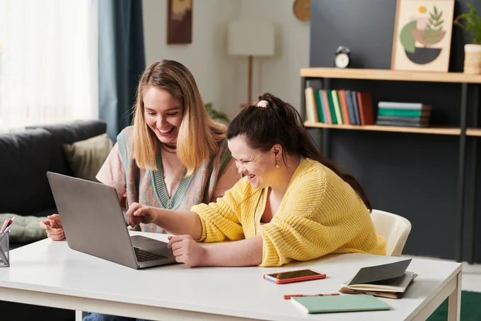 A young woman with disabilities works in a laptop with a colleague