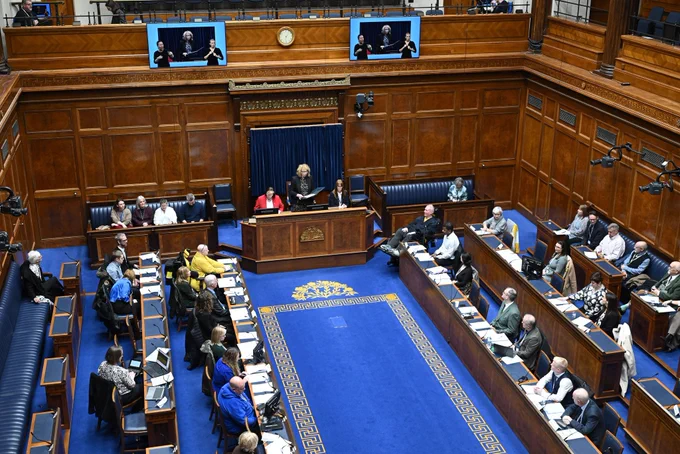 The photograph shows a busy and full Assembly Chamber. The Principal Deputy Speaker is standing, addressing the participants of the Disabled People's Parliament.