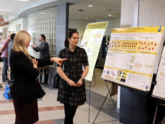 PhD candidate Alyssa Horne discusses her poster with physics alum Dr. Carly Robinson.