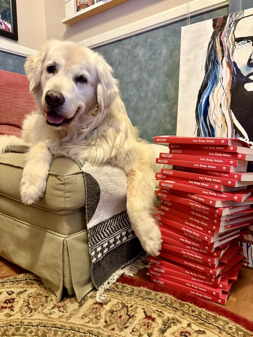 Sampson looking happy by a stack of INSISTENT books. 