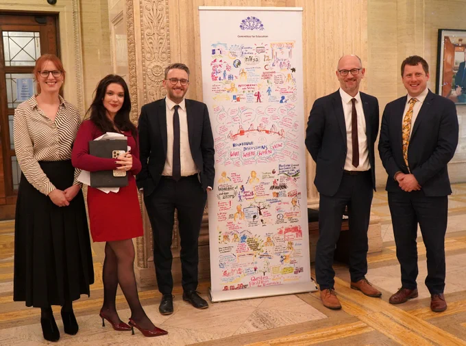 Members of the Education Committee and friends after the Assembly passed its motion on Outdoor Learning in Schools: L-R MLAs Michelle Guy, Cara Hunter, Chairperson Nick Mathison, former Committee member Peter Martin and outdoor practitioner, Andrew McMurray. Artwork by Helen Gomez