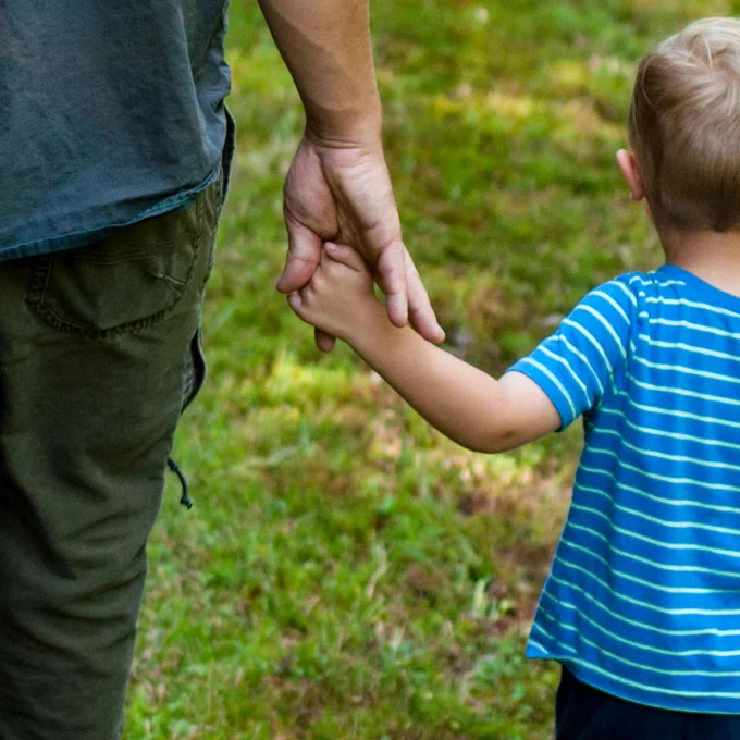 A dad and a boy holding hands
