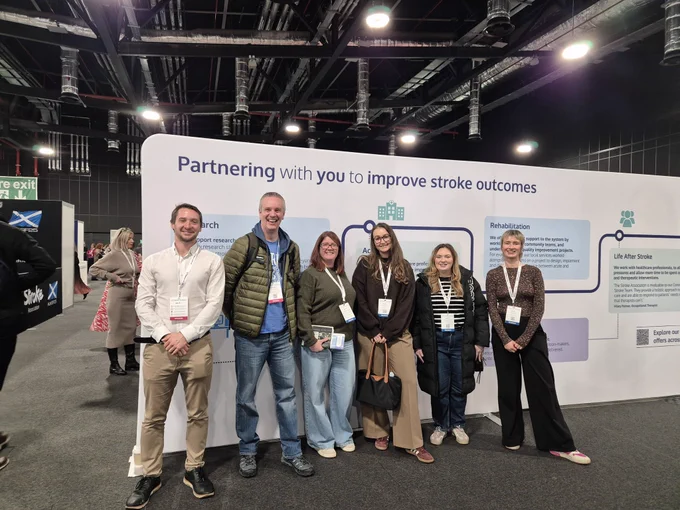 6 people in front of a stroke association stall saying partnering with you to improve stroke outcomes 