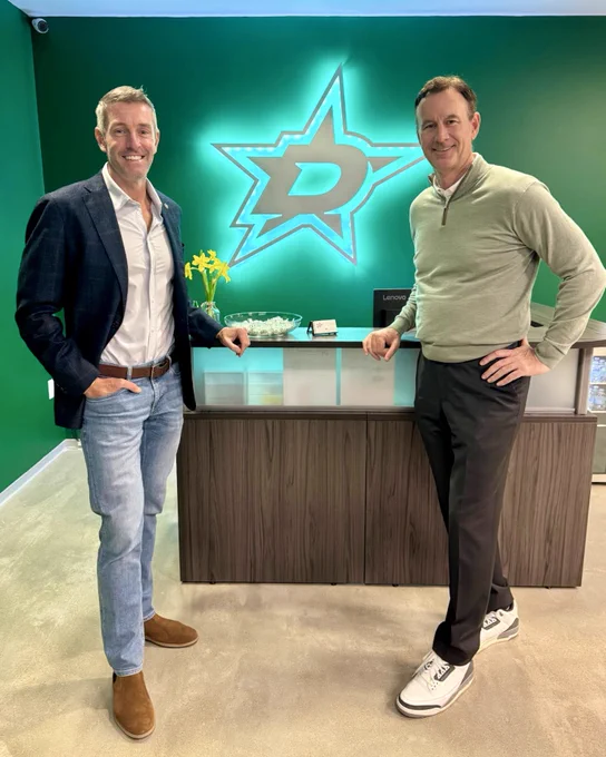 Chad West and Brad Alberts pose for a smiling photo at the front desk of the Stars’ Dallas headquarters