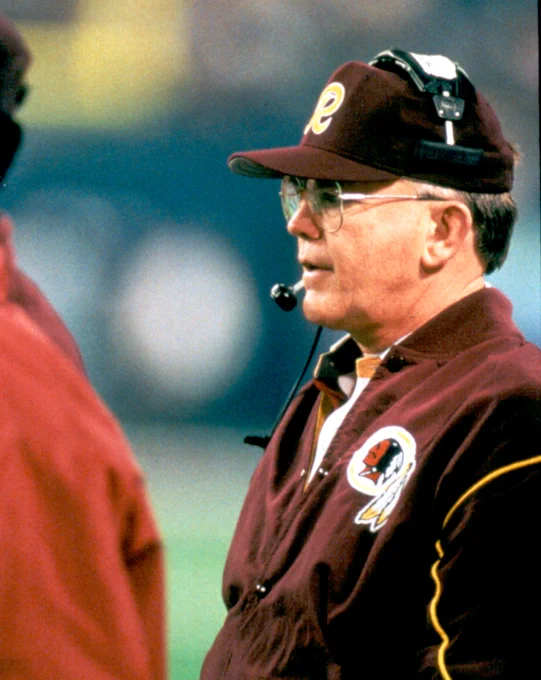 Photo of Joe Gibbs. He is wearing a burgundy hat and jacket. He is also wearing a headset.