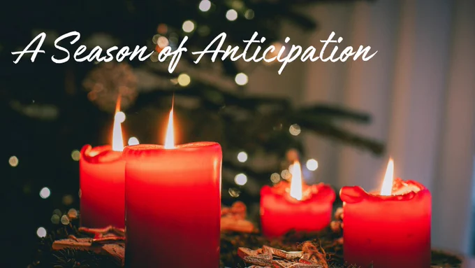 Four red Advent candles glow warmly with blurred Christmas lights twinkling in the background. The words “A Season of Anticipation” appear in white script at the top.