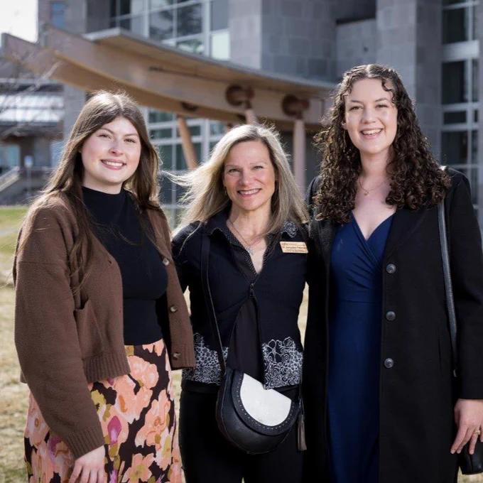 Dr. Jacqui Pettersen stands outdoors on a lawn together with UNBC graduate Jenna Rea and NMP graduate Katherine Bailey.