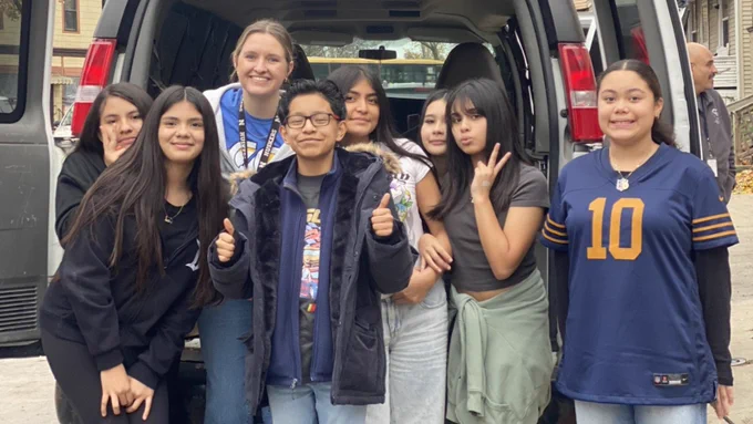 Group of student council Students smiling in front of a van with their teacher