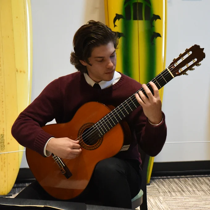 Student performing on the guitar in the Surfboard Room.