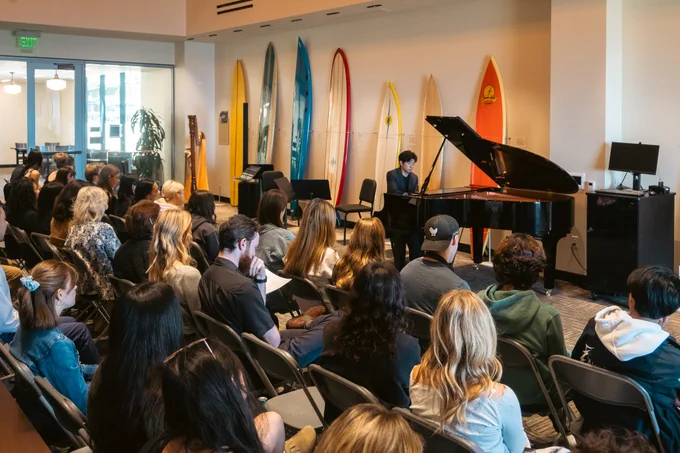 Student performing on the piano in the Surfboard Room.