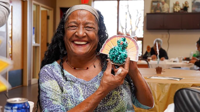 Senior Center client holding a handmade turkey craft
