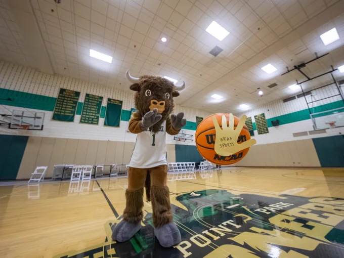 Black Diamond II, Point Park University's mascot, passing a basketball with a thankful hand on the ball.