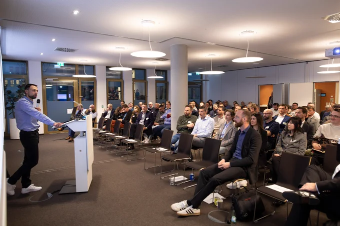 Christoph Wilhein, Zentrale Kriminalinspektion Braunschweig spricht am Rednerpult zu großem Publikum in modernem Konferenzraum bei der der Jahrestagung der Sicherheitskooperation Cybercrime 2025.
