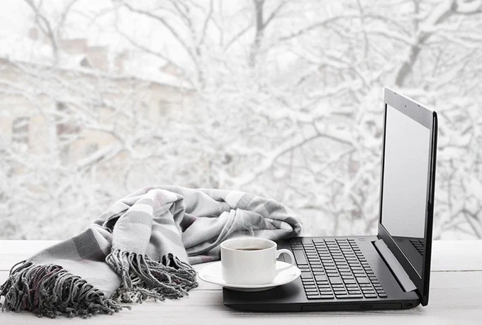 Photograph of a desk, laptop, coffee cup, and scarf 