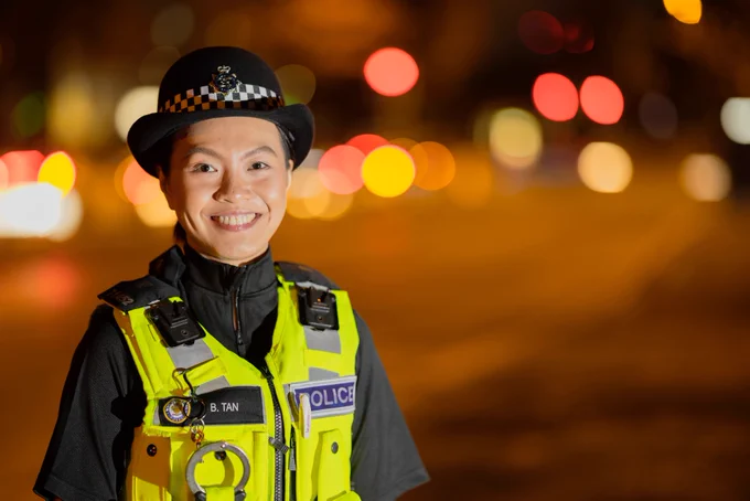 a female officer is standing in uniform and smiling