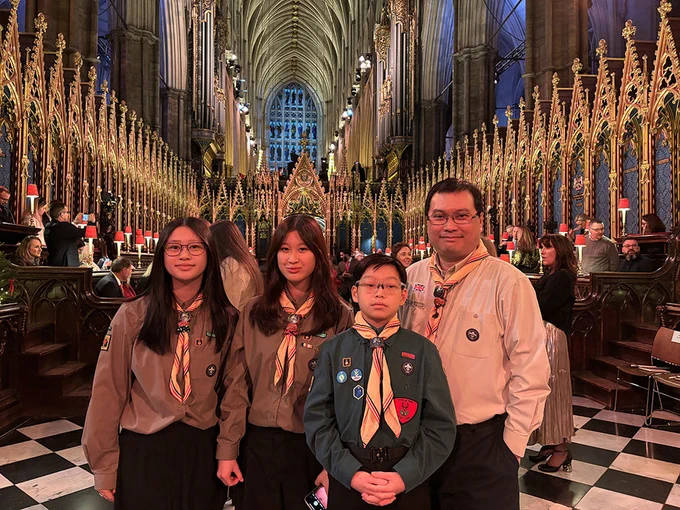 Four Scouts wearing uniforms stand smiling inside Westminster Abbey.