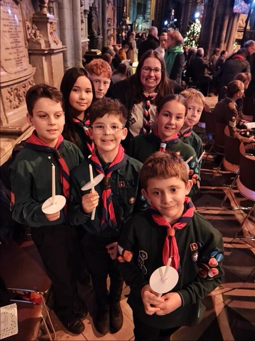 Group of Scouts holding candles inside a church, smiling into the camera.