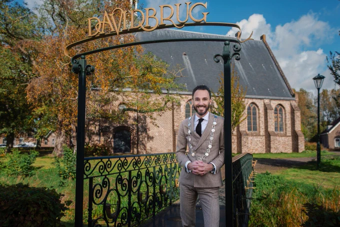 Burgemeester Arno Scheepers, Voorne aan Zee, staat op de Davidbrug voor een kerk.