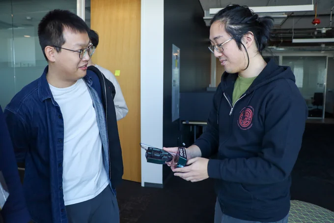 Two Team Atlanta members admire the miniature AIxCC trophies