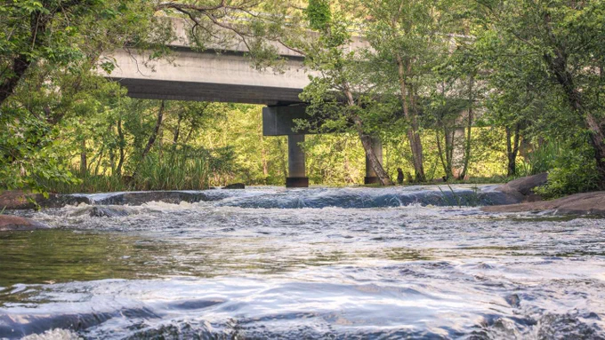 The Neuse River flows under a bridge on a sunny day 