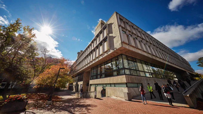 Exterior view of the McLaughlin Library at the University of Guelph on a sunny day, with people walking around and a ramp leading to the entrance.