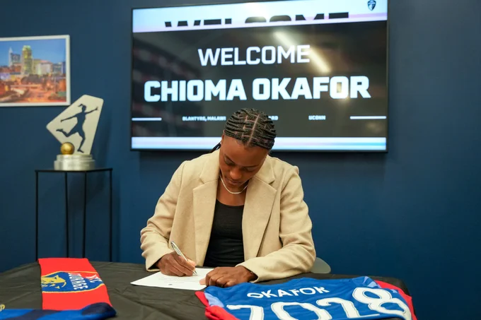 Chioma Okafor signing a contract with welcome graphic on the screen behind her