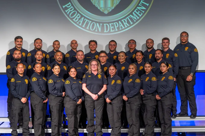 A group of probation corrections  officers posing together for a graduation celebration photo, with the Chief Probation Officer.
