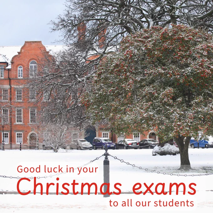 Snow-covered landscape at Trinity College with a traditional brick building in the background. A vibrant tree with red berries stands in the foreground. Text wishes students good luck in their Christmas exams.