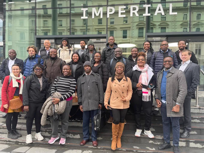 Delegates stand outside of Imperial Colleague London's headquarters, smiling towards the camera.