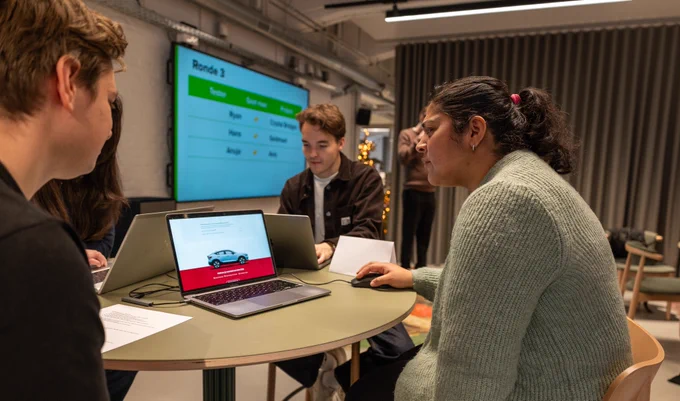 three people at a table one person is looking at a laptop