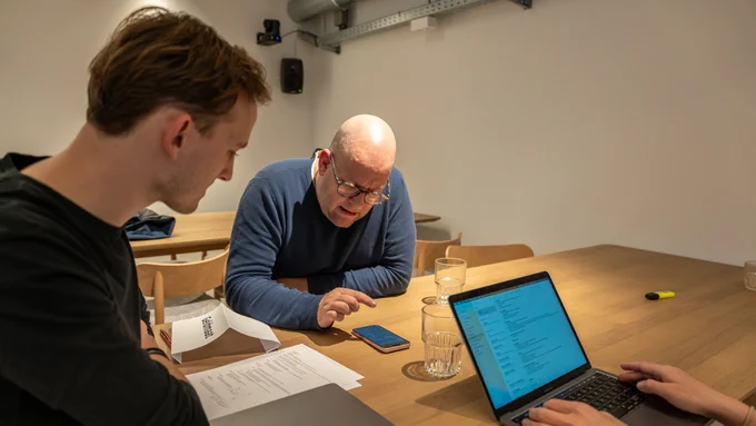 Two people at a table on is looking at a phone